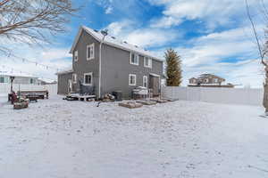 Snow covered back of property featuring central AC unit