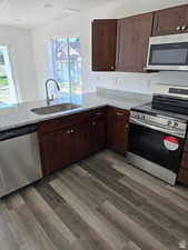 Kitchen featuring appliances with stainless steel finishes, light stone countertops, sink, and kitchen peninsula