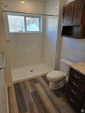 Bathroom with wood-type flooring, a shower, vanity, and toilet