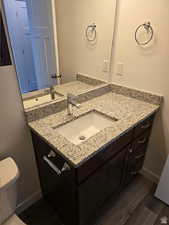 Bathroom with vanity, hardwood / wood-style flooring, and toilet