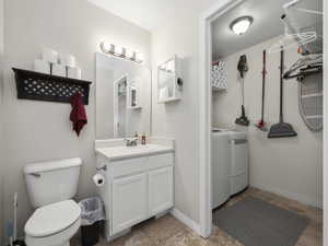 Bathroom with vanity, independent washer and dryer, and toilet