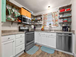 Kitchen featuring appliances with stainless steel finishes, sink, a textured ceiling, and white cabinets