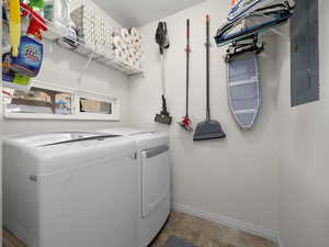 Laundry room with electric panel and washer and clothes dryer