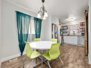 Dining area featuring sink, a textured ceiling, light hardwood / wood-style flooring, and a chandelier