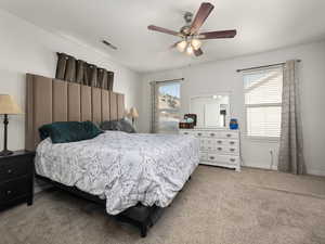 Bedroom featuring multiple windows, light colored carpet, and ceiling fan