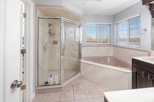 Bathroom with vanity, tile patterned flooring, and shower with separate bathtub