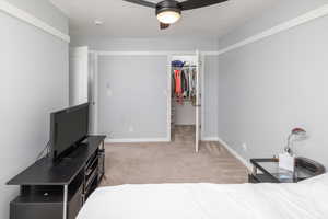 Bedroom with light carpet, a walk in closet, a closet, and ceiling fan