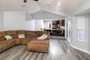 Living room with ceiling fan, lofted ceiling, and light hardwood / wood-style flooring