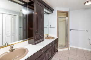 Bathroom featuring tile patterned flooring, vanity, toilet, and a shower with shower door