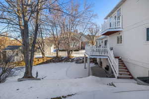 Yard covered in snow featuring a balcony and a deck