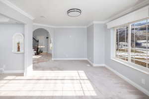 Family room with ornamental molding and light carpet