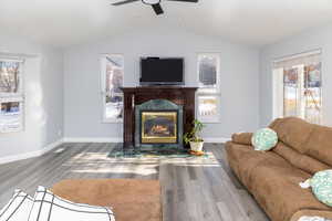 Living room with hardwood / wood-style flooring, a high end fireplace, ceiling fan, and vaulted ceiling