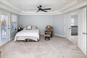 Carpeted bedroom with crown molding, ceiling fan, a raised ceiling, and access to exterior balcony