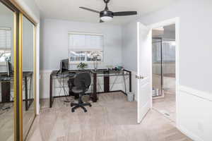 Carpeted office featuring ceiling fan