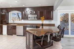 Kitchen featuring sink, a breakfast bar, dark stone countertops, dark brown cabinets, and stainless steel appliances