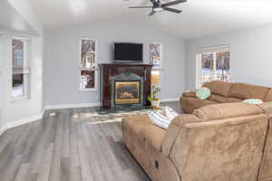 Living room featuring hardwood / wood-style floors, a high end fireplace, ceiling fan, and vaulted ceiling