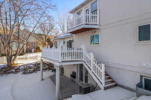 Snow covered rear of property featuring a balcony and deck