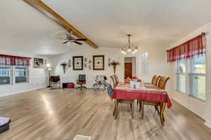 Dining space with a textured ceiling, light hardwood / wood-style flooring, and vaulted ceiling with beams