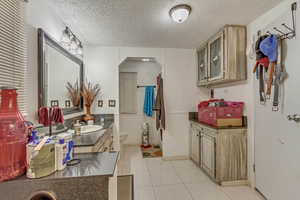 Bathroom with vanity, toilet, tile patterned flooring, and a textured ceiling