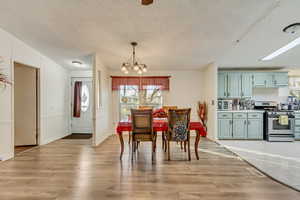 Dining area with a notable chandelier, light hardwood / wood-style flooring, and a textured ceiling