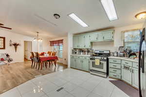 Kitchen with pendant lighting, lofted ceiling, stainless steel range with gas cooktop, and light tile patterned floors