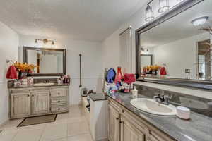 Bathroom featuring vanity, tile patterned flooring, and a textured ceiling