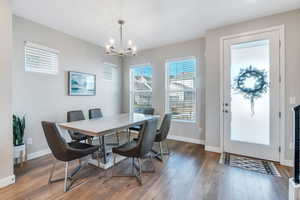 Dining area with dark wood-type flooring and an inviting chandelier