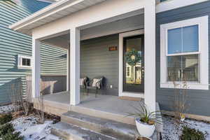 Snow covered property entrance featuring a porch