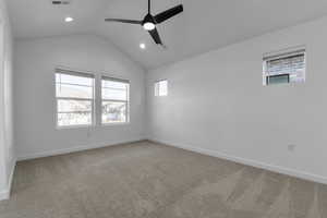 Carpeted empty room with lofted ceiling and ceiling fan