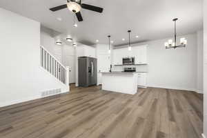 Kitchen featuring pendant lighting, stainless steel appliances, a center island, and white cabinets