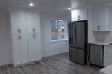 Kitchen with black refrigerator, white cabinetry, and dark wood-type flooring