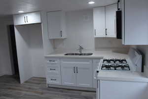 Kitchen featuring white cabinetry, sink, and white gas stove