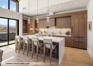 Kitchen with sink, a kitchen island with sink, light hardwood / wood-style floors, a mountain view, and decorative light fixtures