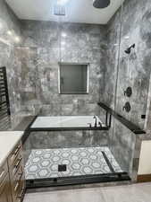 Bathroom featuring vanity, tile patterned floors, plus walk in shower, and tile walls