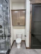 Bathroom featuring an enclosed shower, tile patterned floors, and toilet