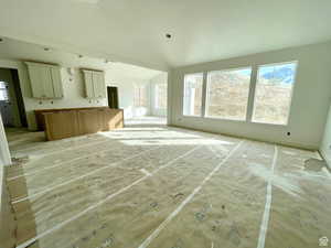 Unfurnished living room featuring lofted ceiling