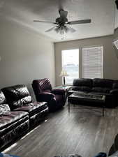 Living room with ceiling fan, wood-type flooring, and a textured ceiling