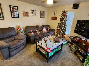 Carpeted living room featuring ceiling fan