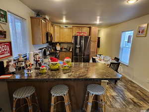 Kitchen with sink, a breakfast bar area, dark hardwood / wood-style flooring, kitchen peninsula, and refrigerator with ice dispenser