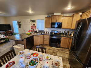 Kitchen with sink, a textured ceiling, dark stone countertops, dark hardwood / wood-style floors, and black appliances