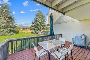 Wooden terrace featuring area for grilling, a mountain view, and a lawn