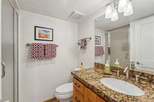 Bathroom featuring vanity, a shower with shower door, and toilet