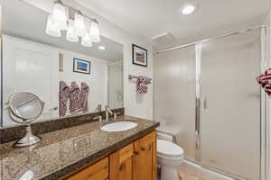 Bathroom featuring walk in shower, vanity, and toilet