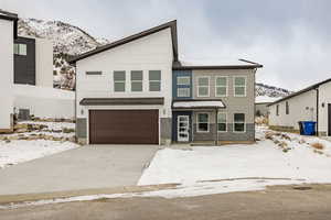 View of front of home with central AC, a garage, and a mountain view