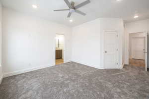 Unfurnished bedroom featuring ceiling fan, carpet, and ensuite bath