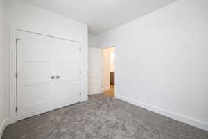 Unfurnished bedroom featuring light colored carpet and a closet