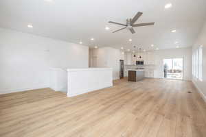 Unfurnished living room with sink, light hardwood / wood-style flooring, and ceiling fan