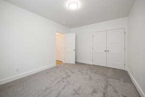 Unfurnished bedroom featuring light carpet and a closet