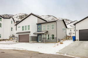 View of front facade with cooling unit, a mountain view, and a garage