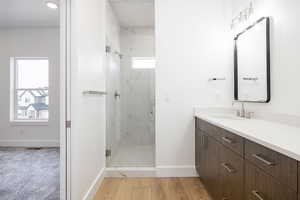 Bathroom featuring hardwood / wood-style flooring, vanity, and a shower with shower door